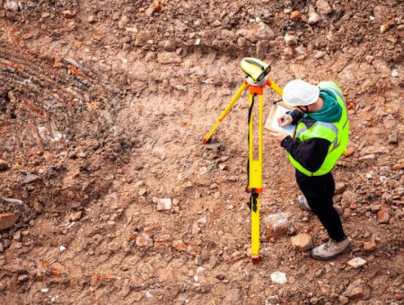 A surveyor on a construction site uses an optical level