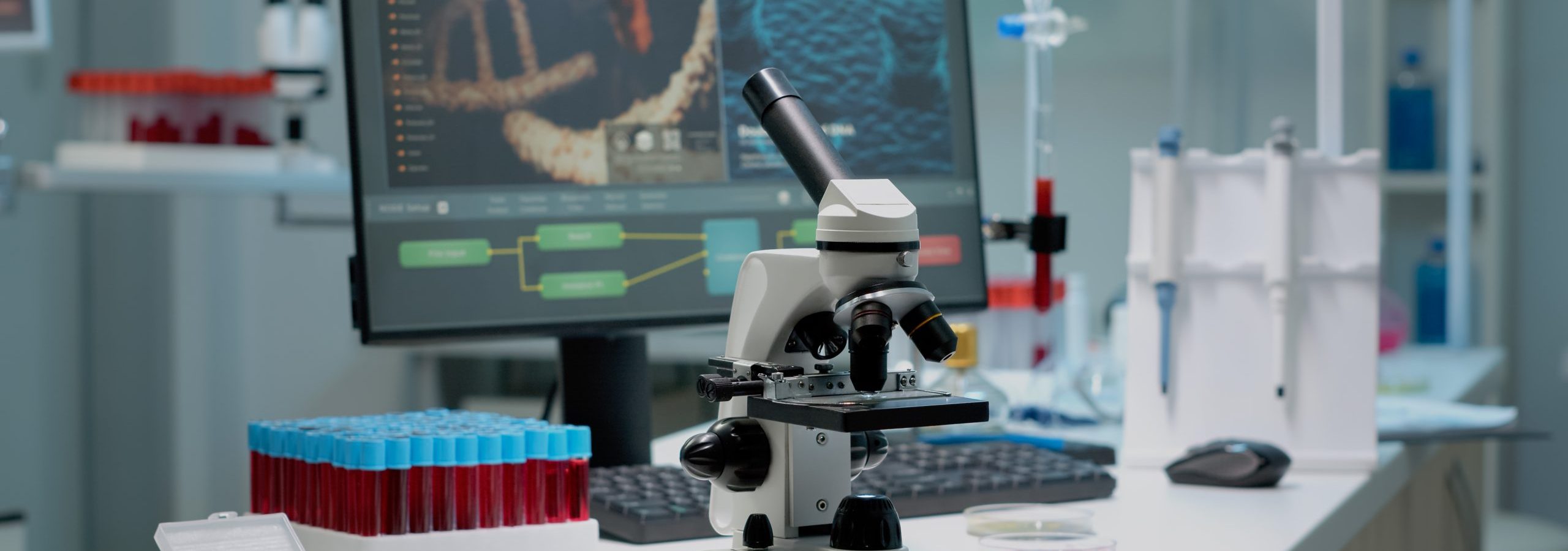 Scientific microscope on laboratory desk with researching instruments at professional workplace. Close up of investigation tool with glass lens for chemical substance lab examination